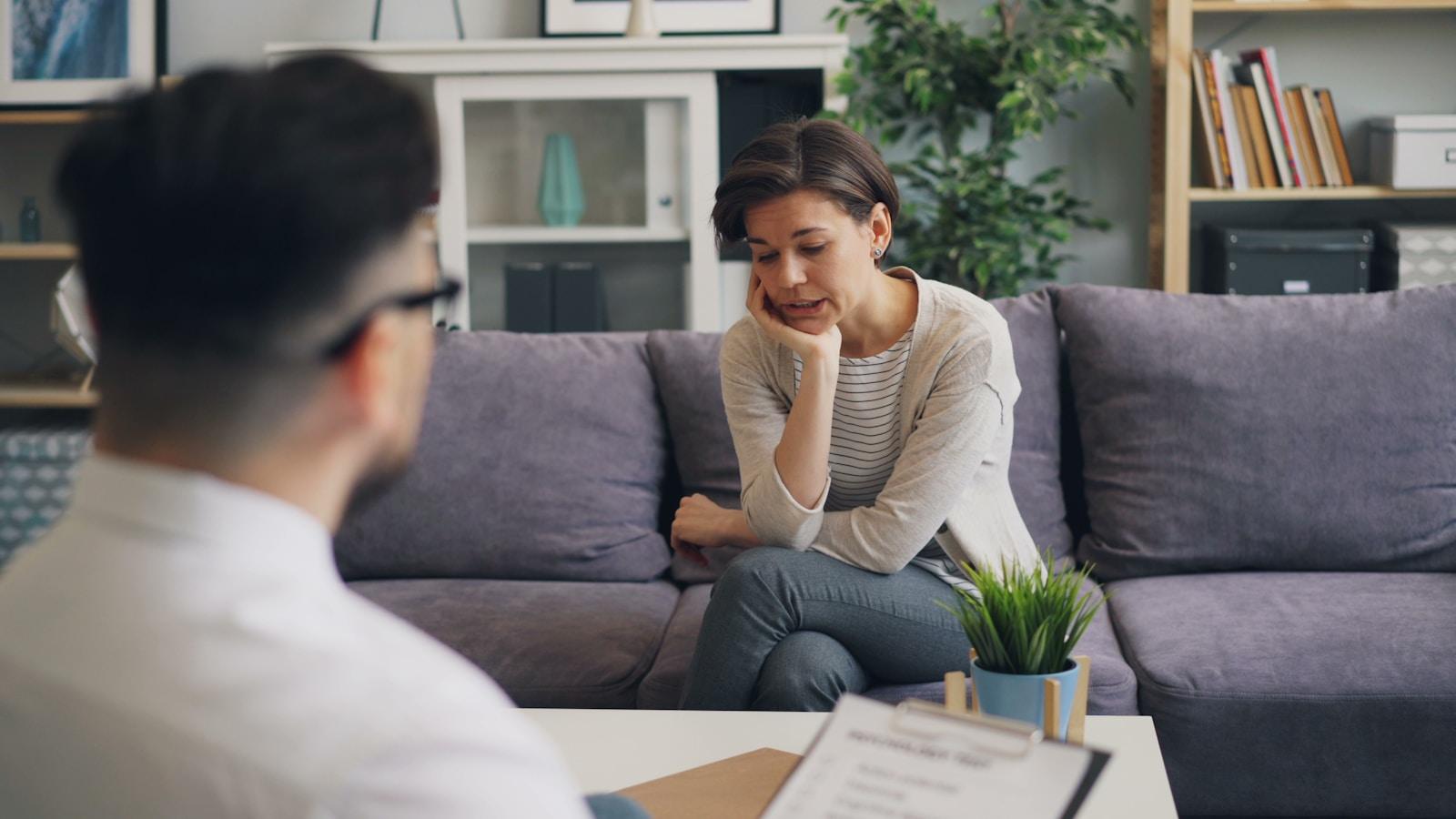 a woman sitting on a couch talking to a man